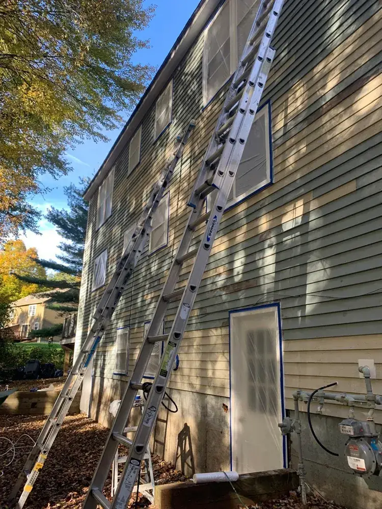 Exterior house painting in progress on a light gray home with staging