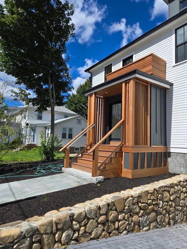 Custom cedar entry portico over a natural stone retaining wall