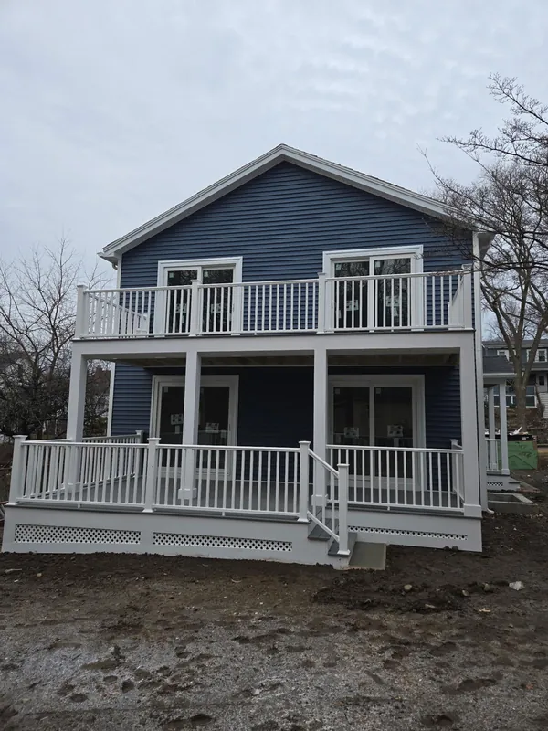 Two-story blue house with double covered porches and white railings