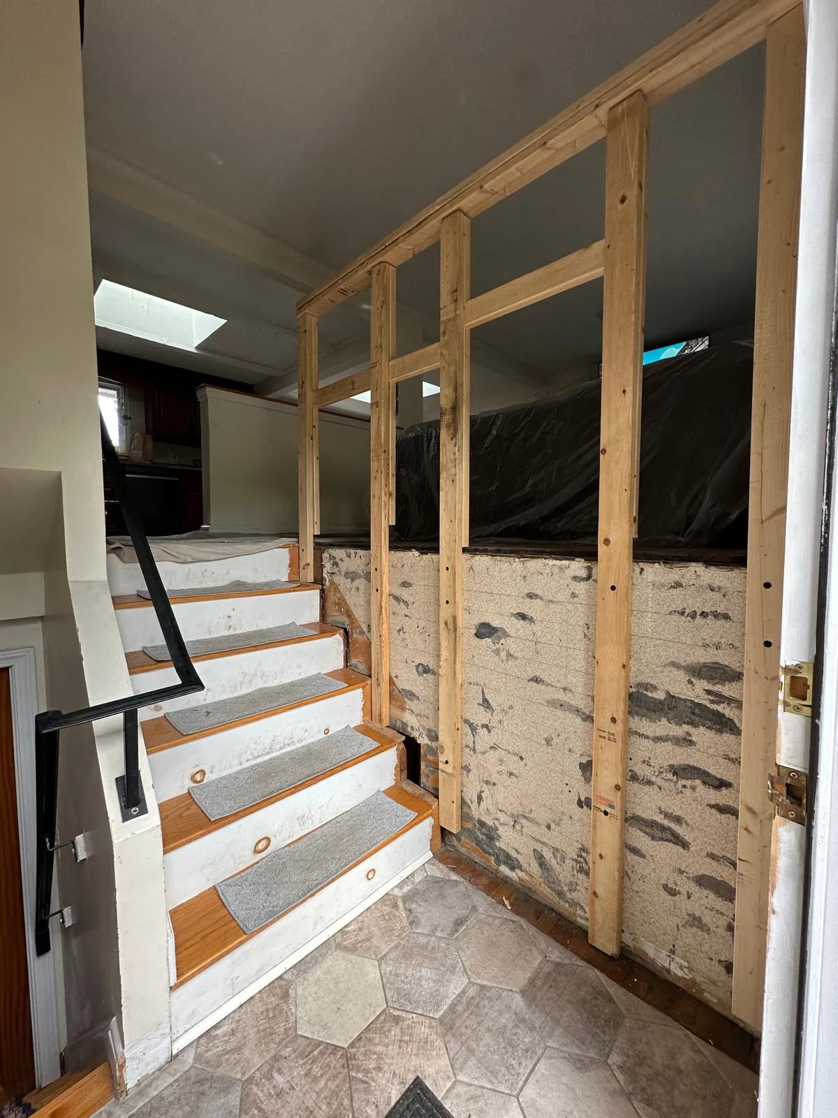 Interior wall being framed mid-remodel, next to a protected staircase