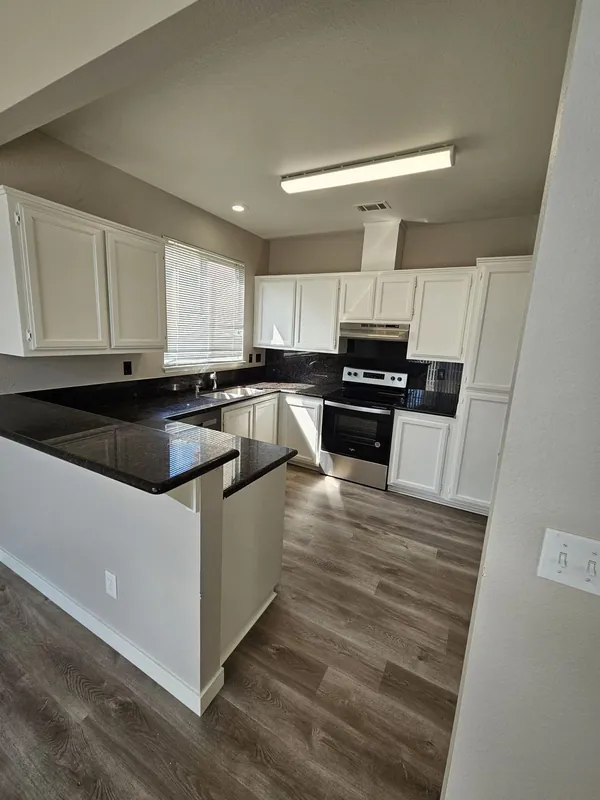 Kitchen remodel with white cabinets, dark granite counters and vinyl plank floor